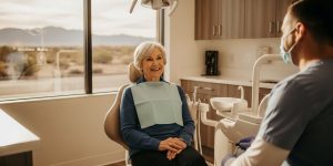 A senior woman in her 60s receiving a dental consultation in a modern Las Vegas dental office, smiling as her dentist explains dental care seniors Las Vegas Nevada options available through Medicare Advantage plans in 2026.